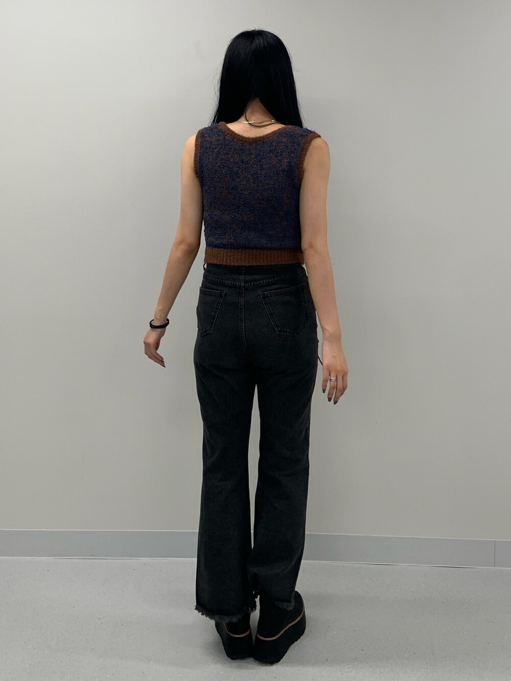 ブラック系のデニムパンツ、ブラック系のブーツ、ブラウン系のニット/セーターを着用したレディースの夏コーディネートの4枚目の写真