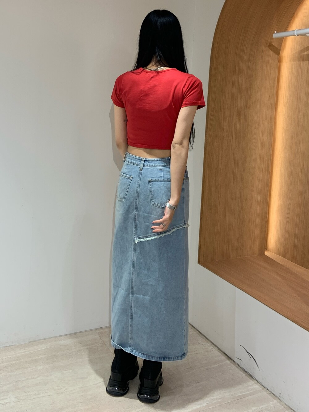 レッド系のTシャツ/カットソー、ブルー系のデニムスカート、ブラック系のブーツを着用したレディースの春コーディネートの4枚目の写真