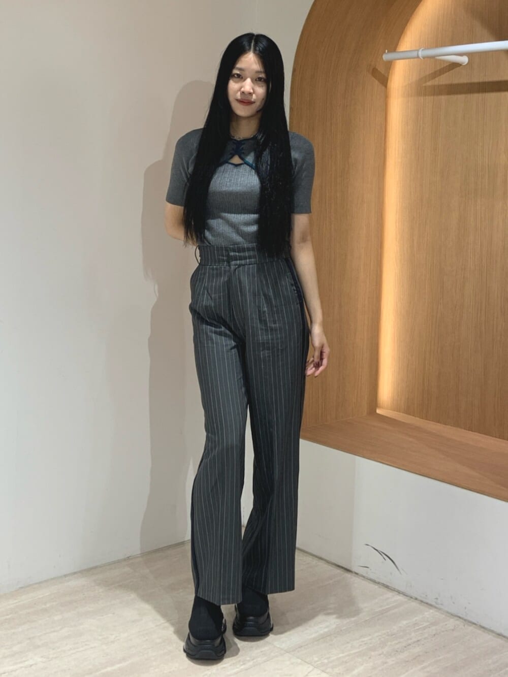 ブラック系のブーツ、グレー系のニット/セーター、グレー系のスラックスを着用したレディースの春コーディネートの2枚目の写真