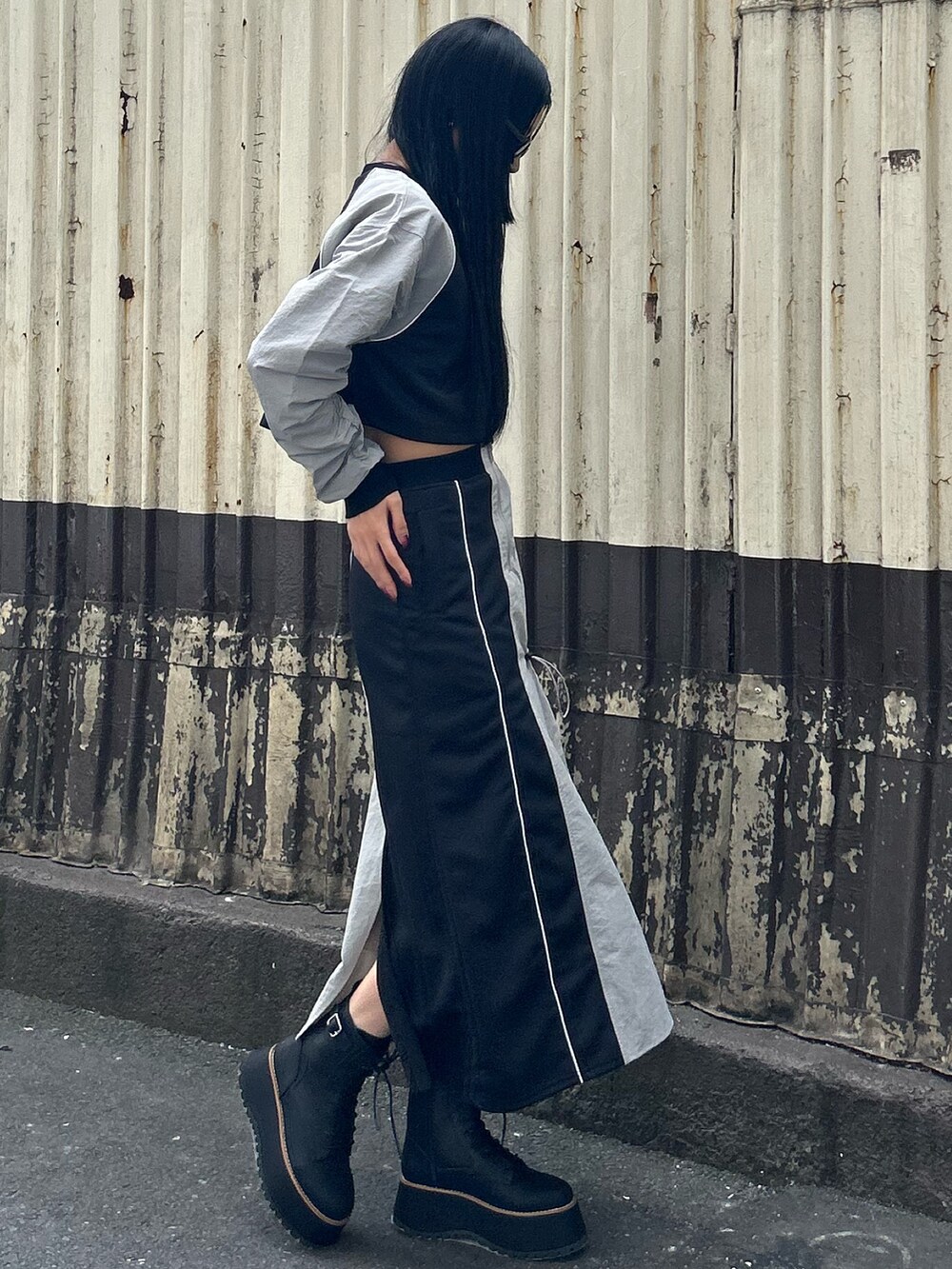 グレー系のTシャツ/カットソー、グレー系のスカート、ブラック系のブーツを着用したレディースの秋コーディネートの2枚目の写真
