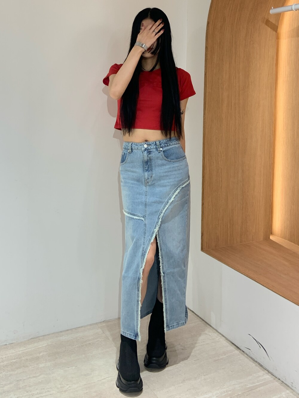 レッド系のTシャツ/カットソー、ブルー系のデニムスカート、ブラック系のブーツを着用したレディースの春コーディネートの2枚目の写真