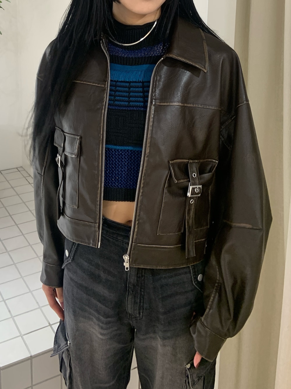 ブラウン系のブルゾン、ブルー系のタンクトップ、ブラック系のデニムパンツを着用したレディースの春コーディネートの5枚目の写真