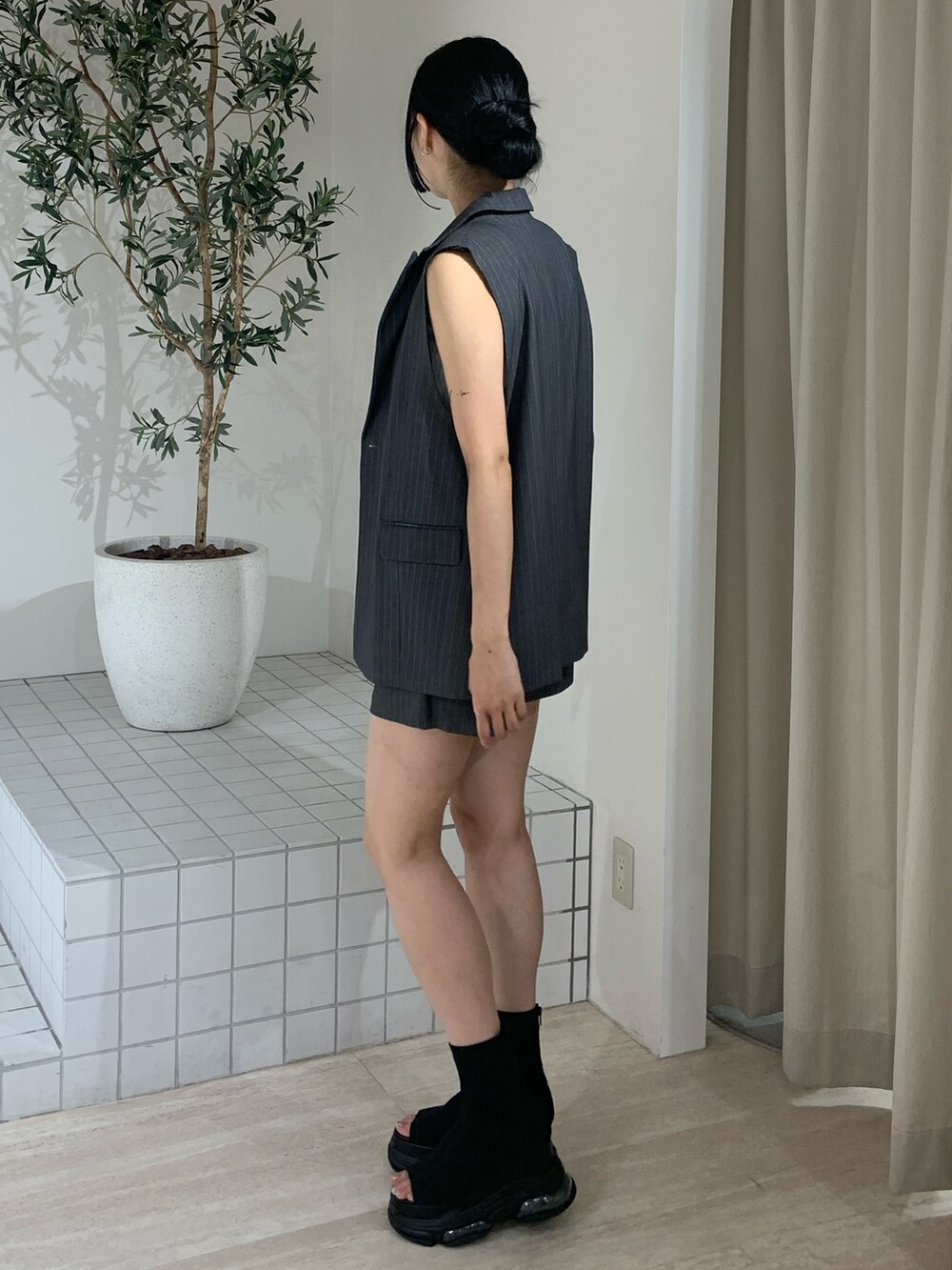 グレー系のベスト、ホワイト系のタンクトップ、グレー系のその他パンツを着用したレディースの夏コーディネートの3枚目の写真