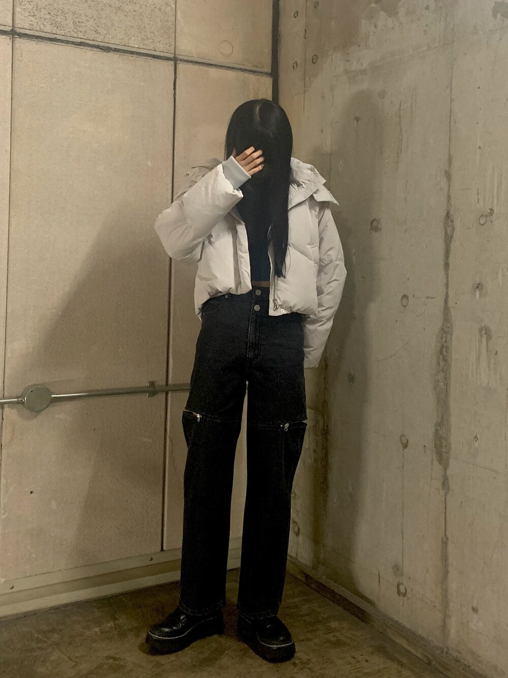 グレー系のダウンジャケット/コート、ブルー系のニット/セーター、ブラック系のデニムパンツを着用したレディースの秋コーディネートの2枚目の写真