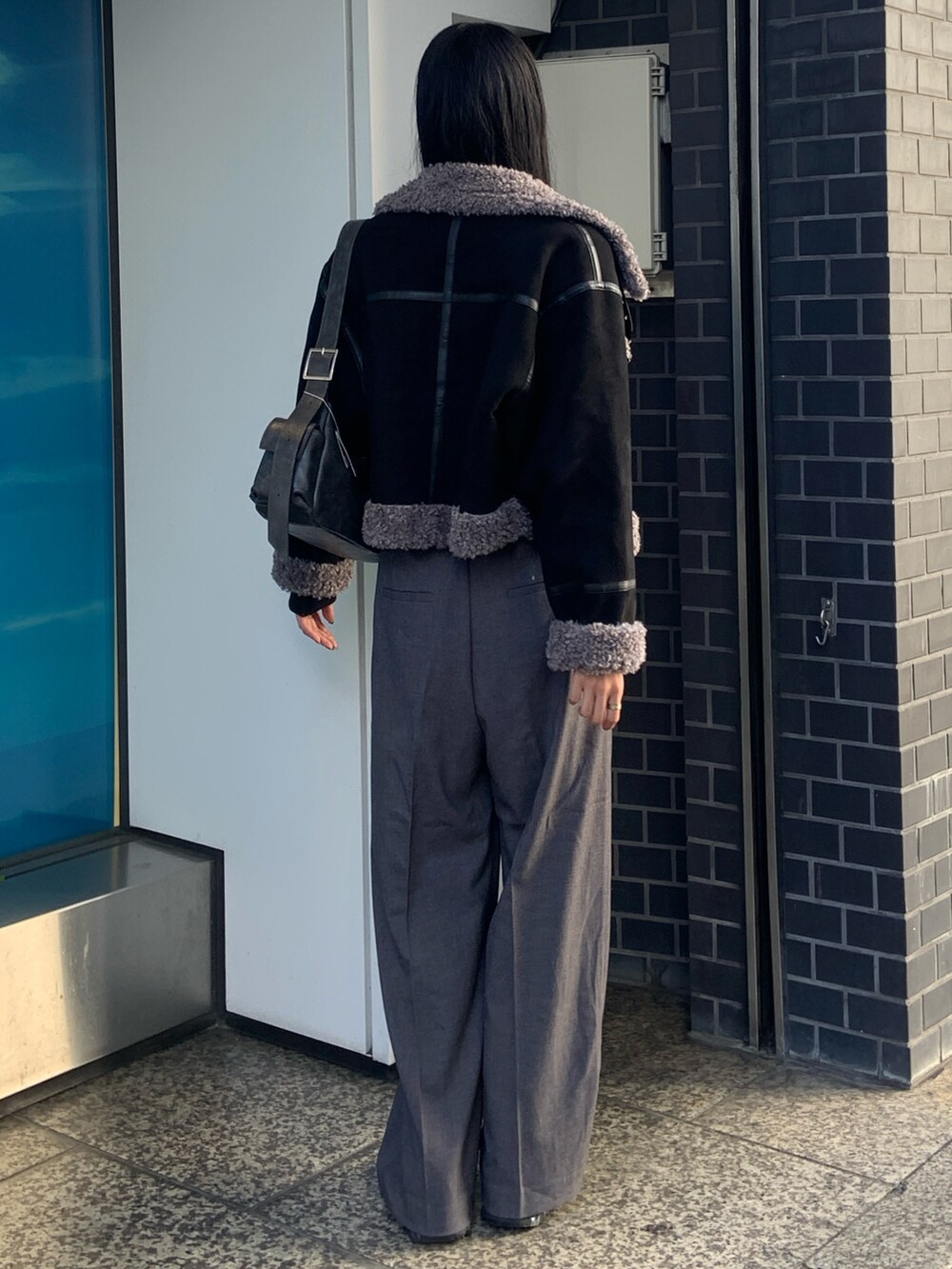ブラック系のニット/セーター、グレー系のその他パンツ、ブラック系のムートンコートを着用したレディースの冬コーディネートの4枚目の写真