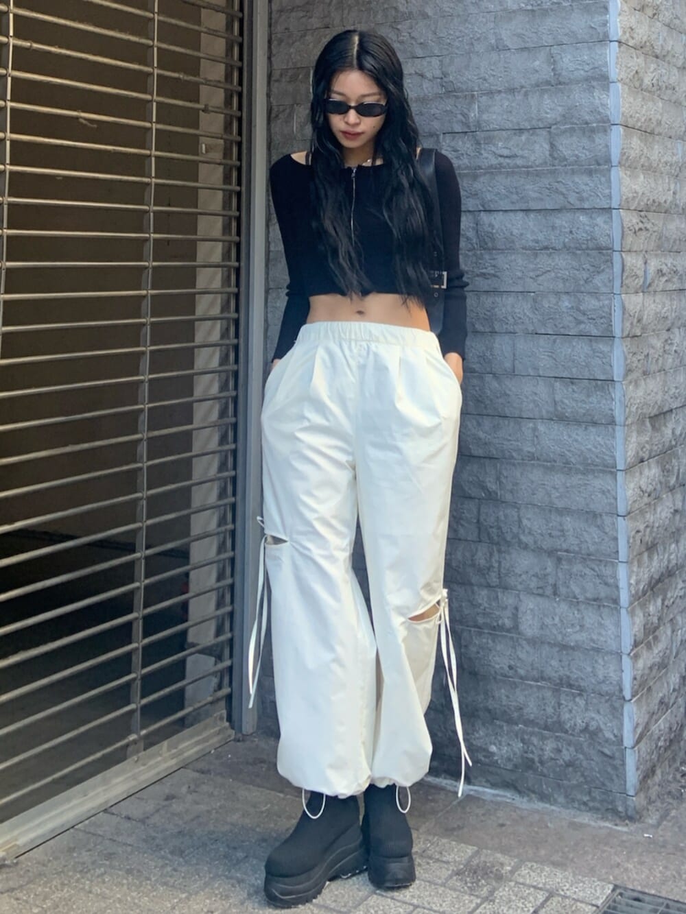 ブラック系のニット/セーター、ホワイト系のその他パンツ、ブラック系のブーツを着用したレディースの冬コーディネートの2枚目の写真