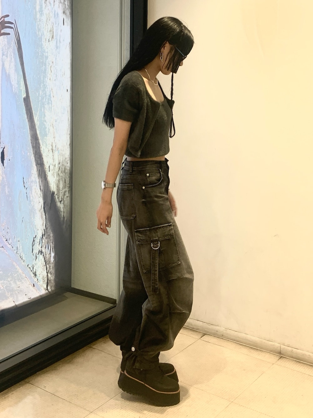 グレー系のニット/セーター、ブラック系のデニムパンツ、ブラック系のブーツを着用したレディースの秋コーディネートの2枚目の写真