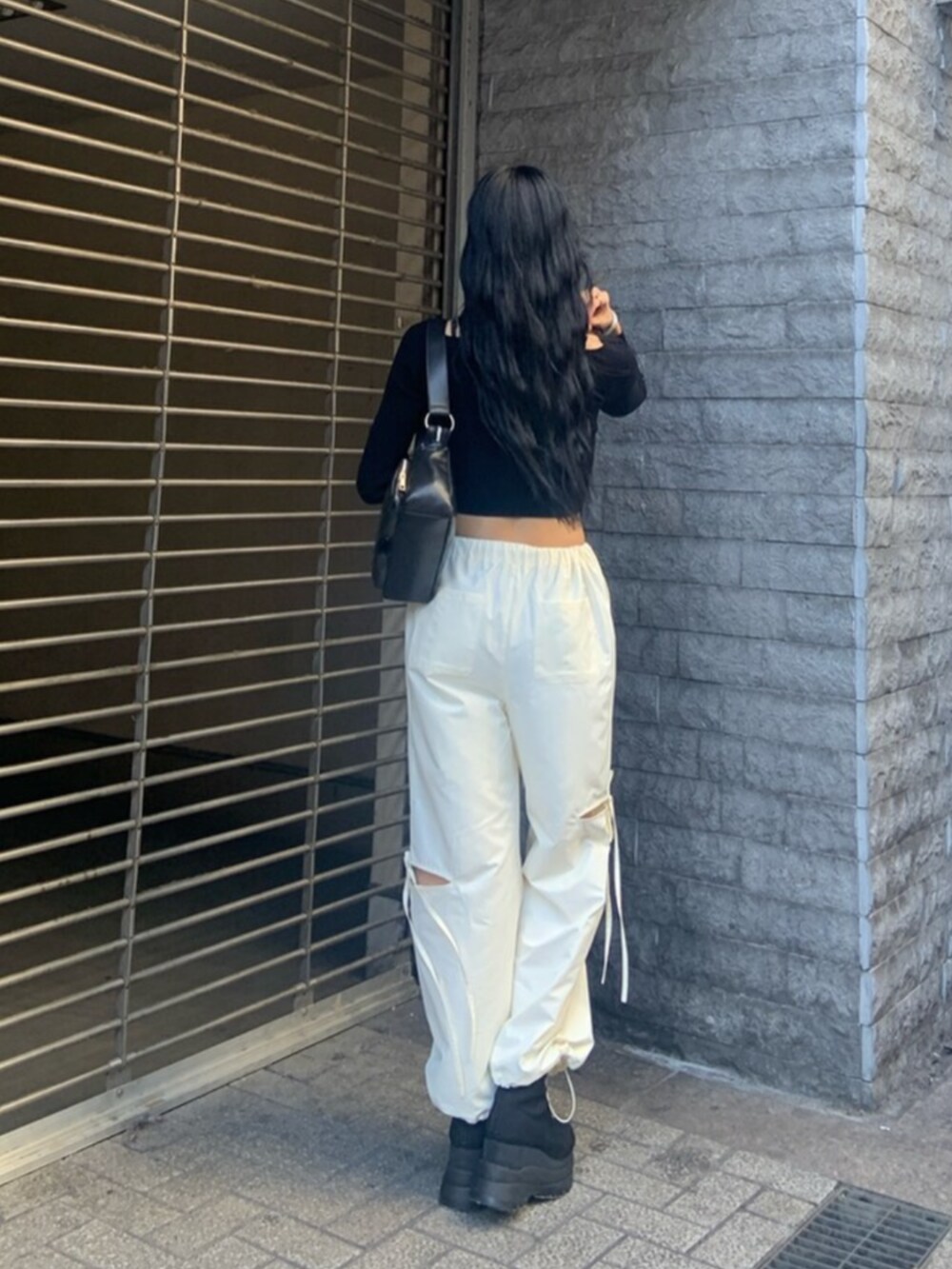 ブラック系のニット/セーター、ホワイト系のその他パンツ、ブラック系のブーツを着用したレディースの冬コーディネートの4枚目の写真