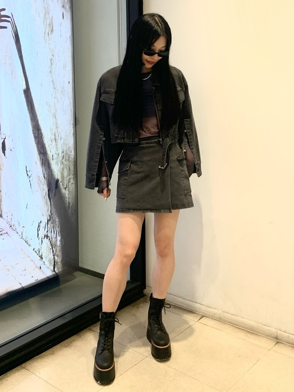 ブラック系のデニムジャケット、ブルー系のTシャツ/カットソー、ブラック系のスカートを着用したレディースの秋コーディネートの4枚目の写真