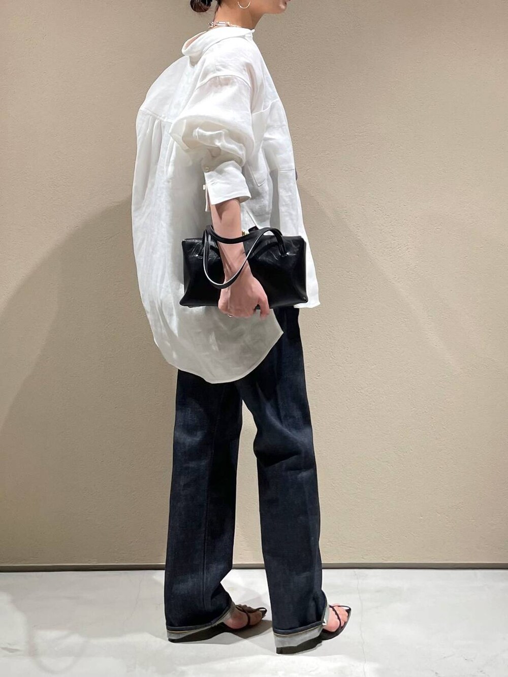 ブルー系のデニムパンツ、ホワイト系のシャツ/ブラウス、ブラック系のベストを着用したレディースの春コーディネートの3枚目の写真
