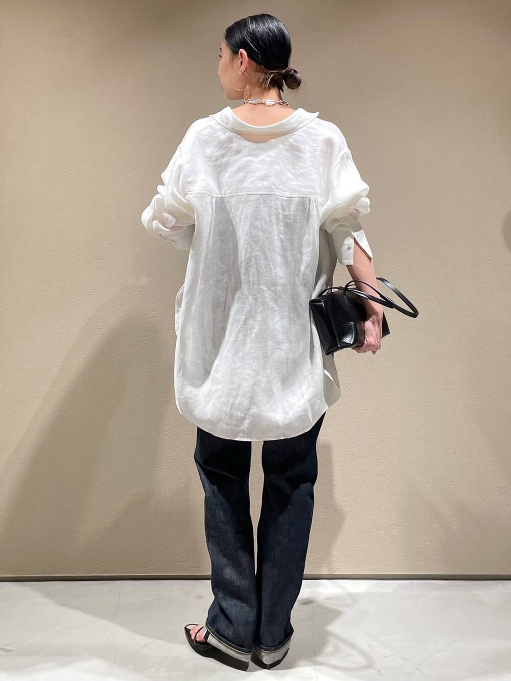 ブルー系のデニムパンツ、ホワイト系のシャツ/ブラウス、ブラック系のベストを着用したレディースの春コーディネートの4枚目の写真