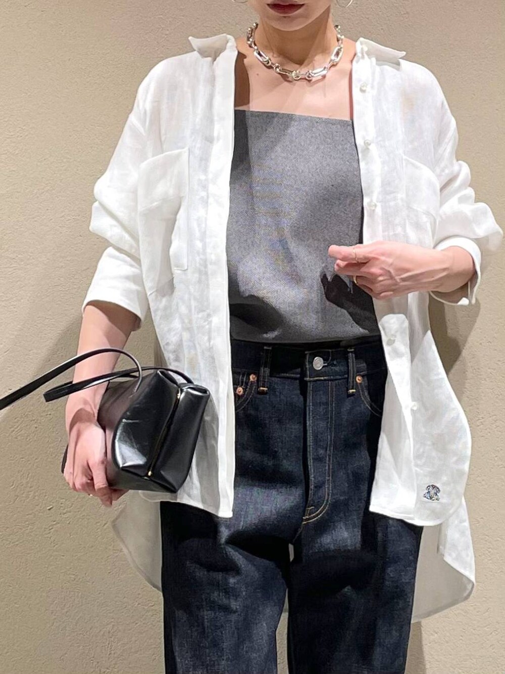 ブルー系のデニムパンツ、ホワイト系のシャツ/ブラウス、ブラック系のベストを着用したレディースの春コーディネートの5枚目の写真