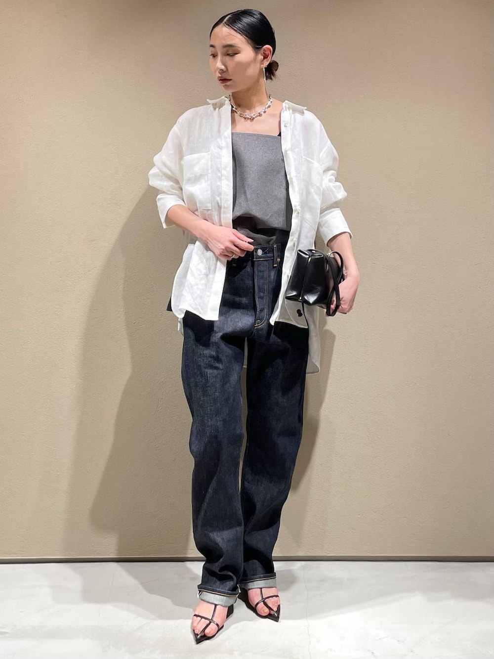 ブルー系のデニムパンツ、ホワイト系のシャツ/ブラウス、ブラック系のベストを着用したレディースの春コーディネートの2枚目の写真