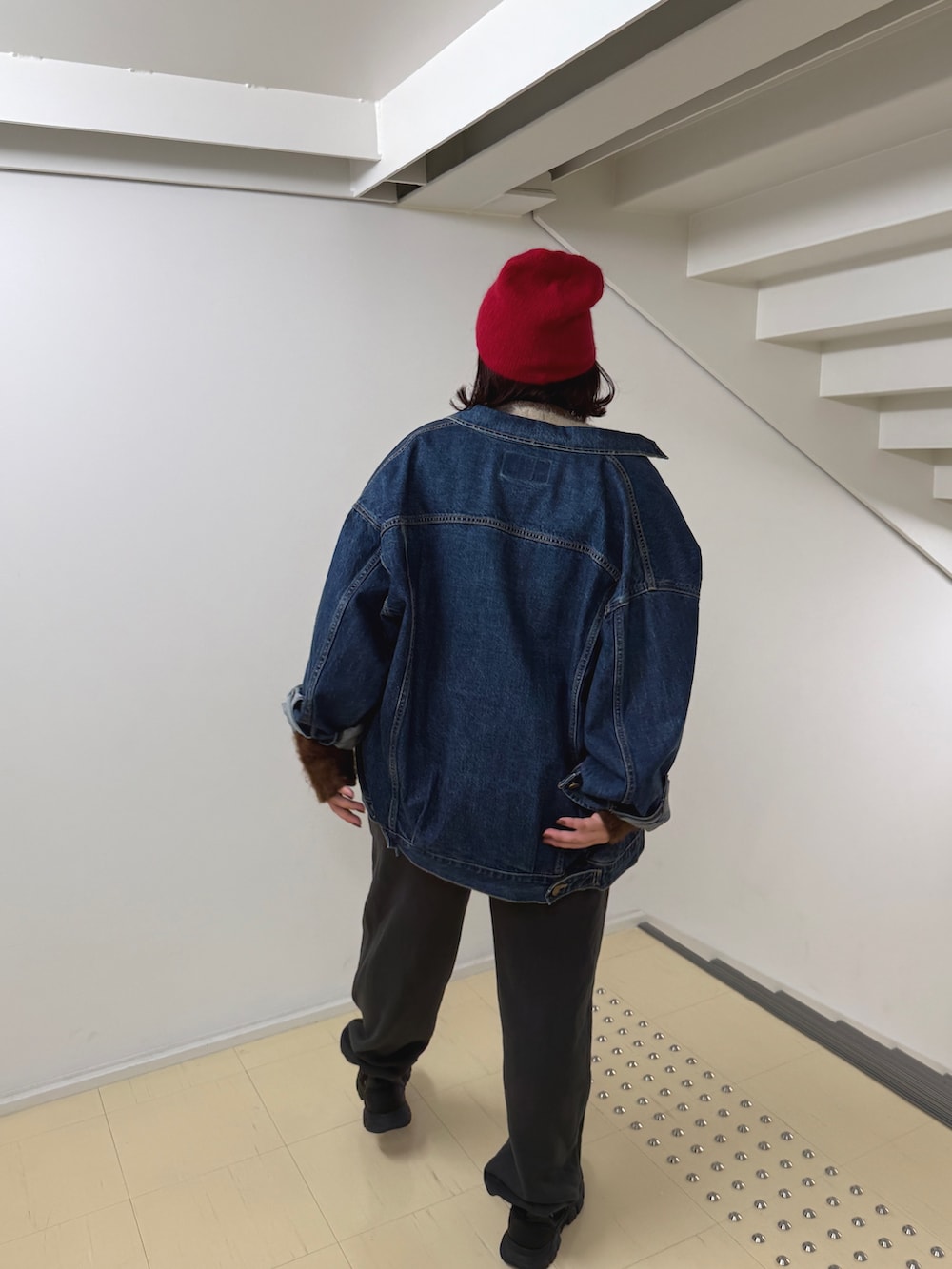 グレー系のニット/セーター、ブルー系のデニムジャケット、グレー系のスウェットパンツを着用したレディースの秋コーディネートの4枚目の写真