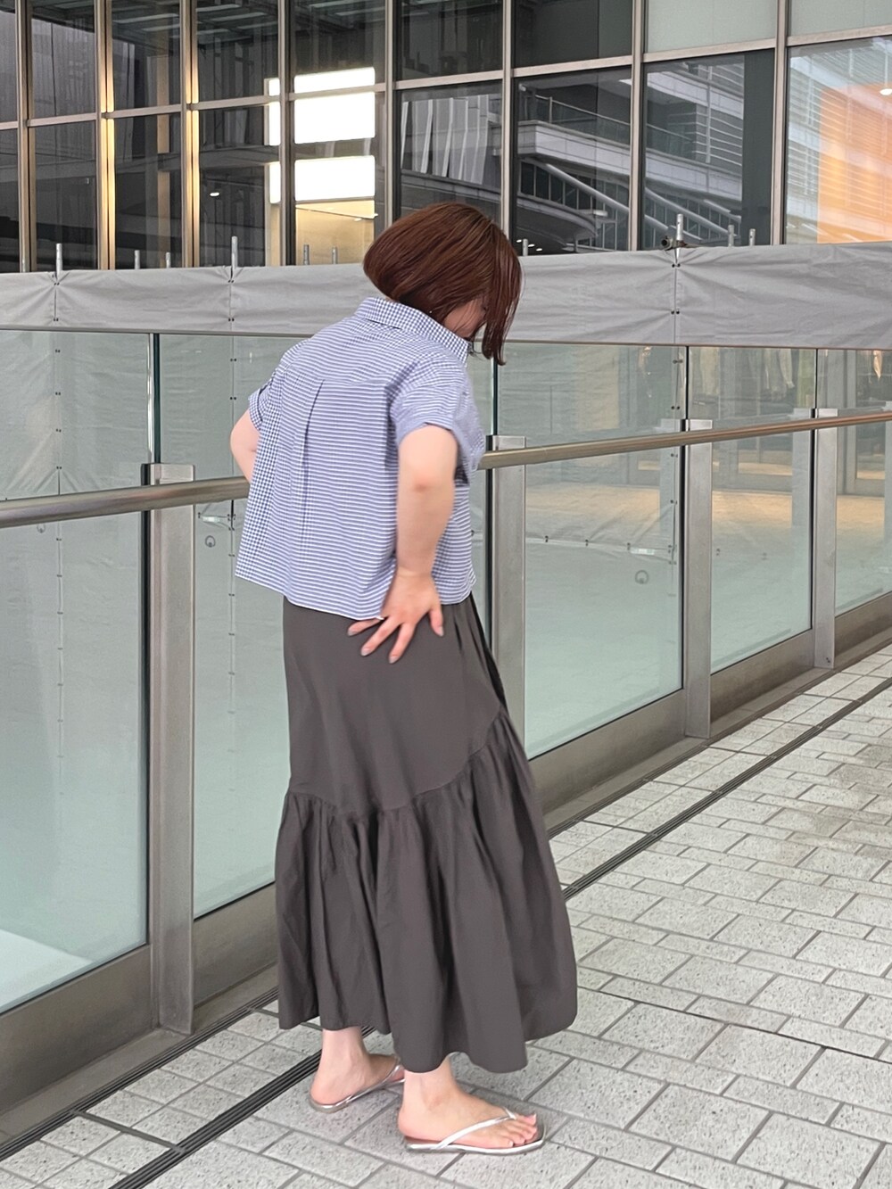 ブラック系のシャツ/ブラウス、グレー系のスカート、シルバー系のサンダルを着用したレディースの夏コーディネートの6枚目の写真
