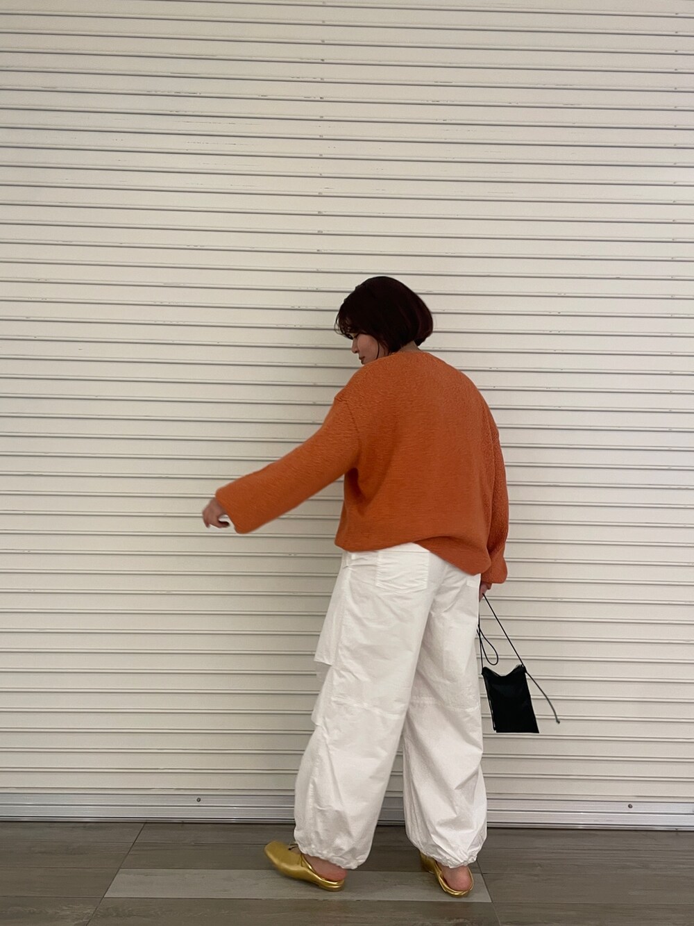 オレンジ系のニット/セーター、ホワイト系のその他パンツ、ゴールド系のパンプスを着用したレディースの冬コーディネートの5枚目の写真