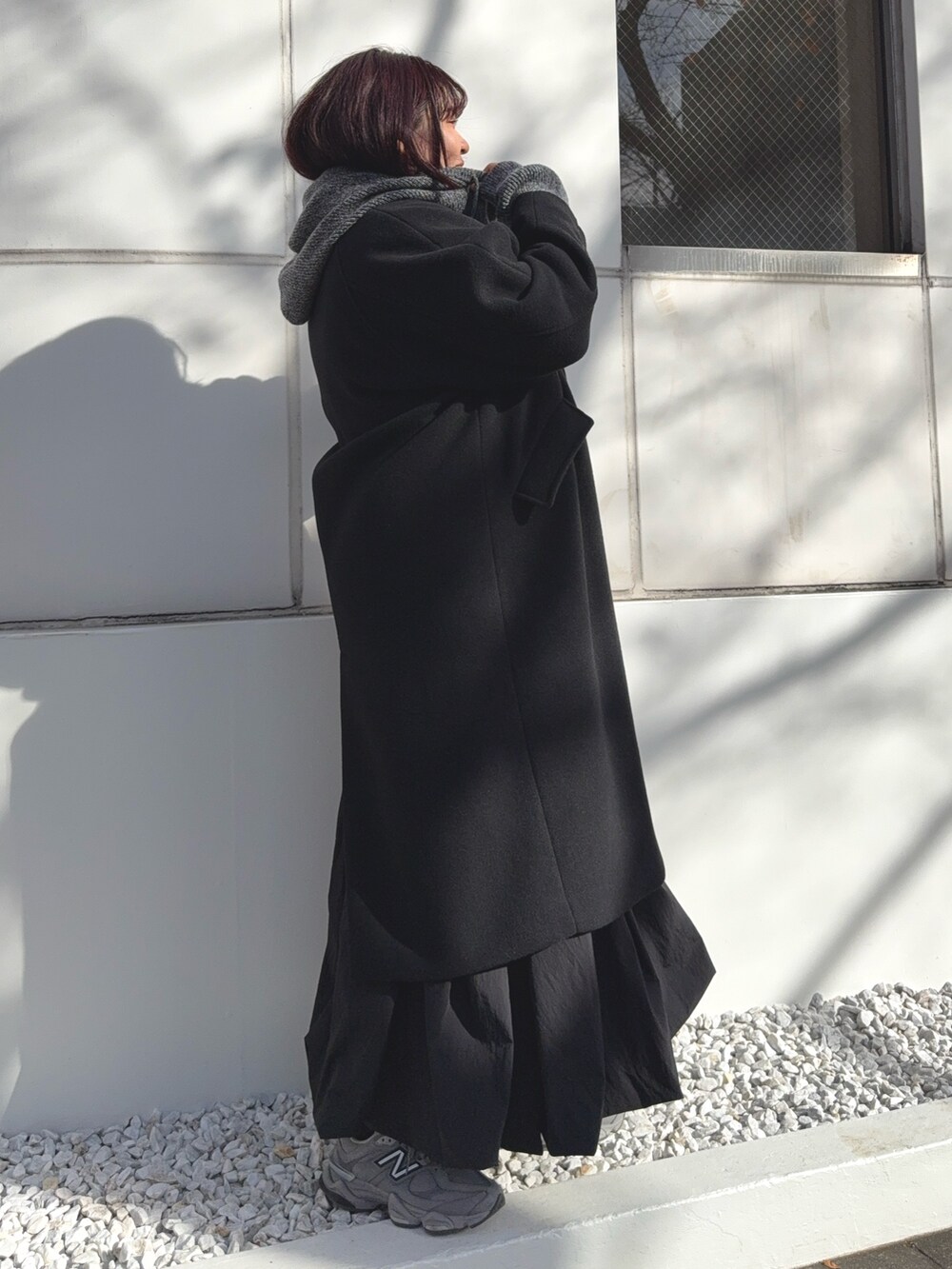 ブラック系のチェスターコート、グレー系のニット/セーターを着用したレディースの冬コーディネートの2枚目の写真