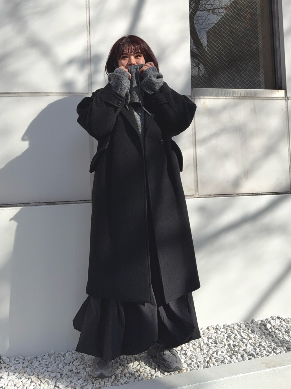 ブラック系のチェスターコート、グレー系のニット/セーターを着用したレディースの冬コーディネートの5枚目の写真