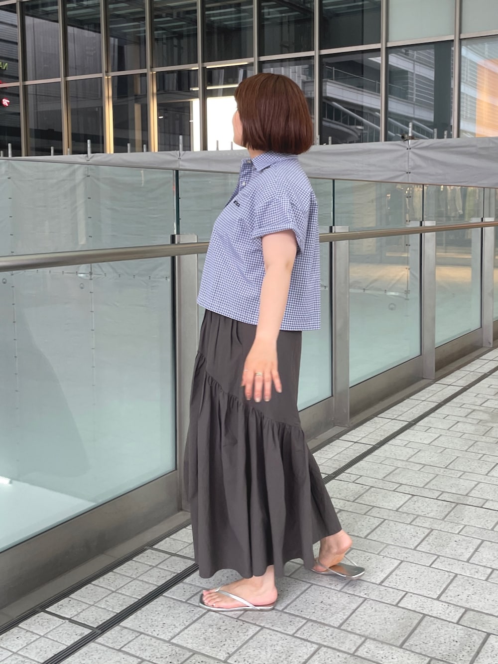 ブラック系のシャツ/ブラウス、グレー系のスカート、シルバー系のサンダルを着用したレディースの夏コーディネートの4枚目の写真