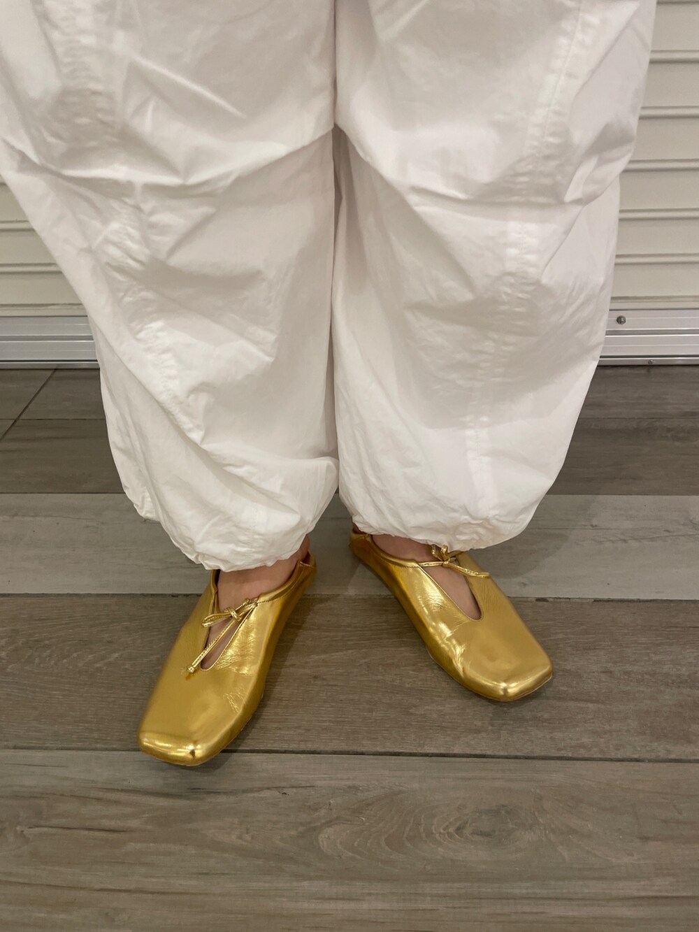 オレンジ系のニット/セーター、ホワイト系のその他パンツ、ゴールド系のパンプスを着用したレディースの冬コーディネートの6枚目の写真