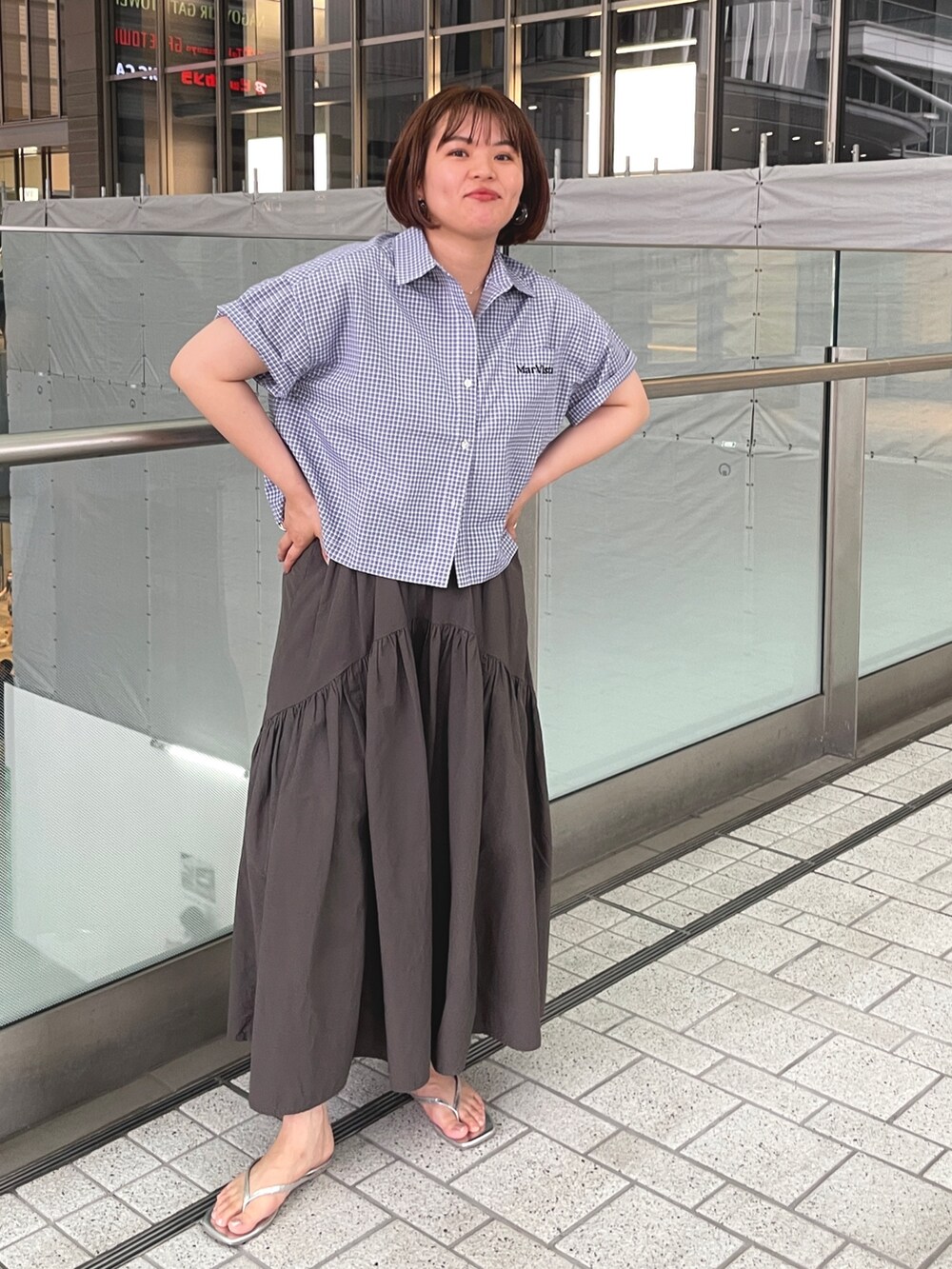 ブラック系のシャツ/ブラウス、グレー系のスカート、シルバー系のサンダルを着用したレディースの夏コーディネートの2枚目の写真