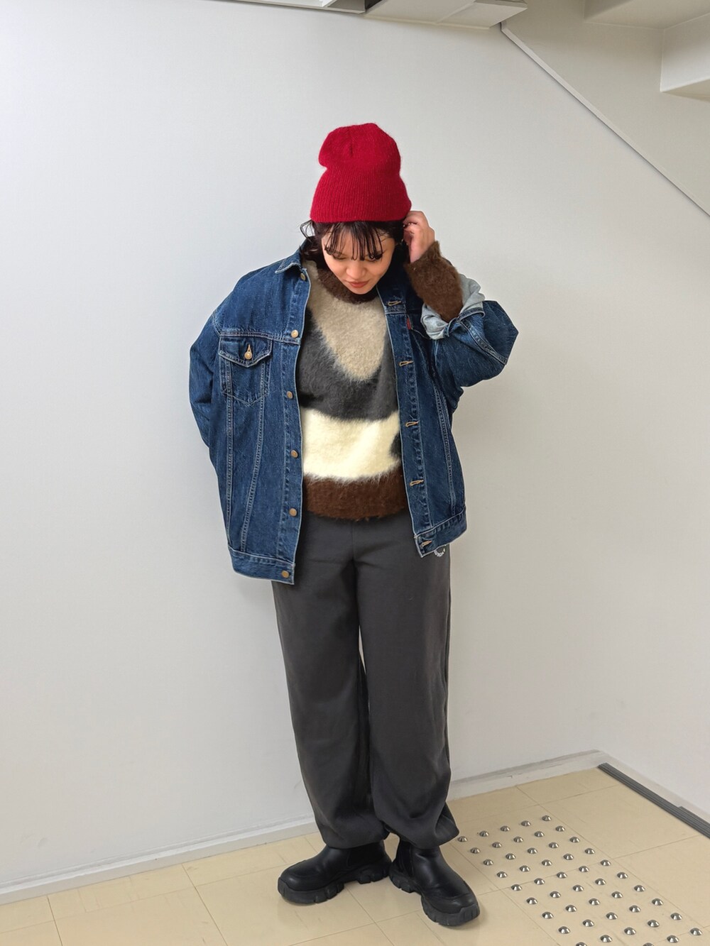 グレー系のニット/セーター、ブルー系のデニムジャケット、グレー系のスウェットパンツを着用したレディースの秋コーディネートの2枚目の写真