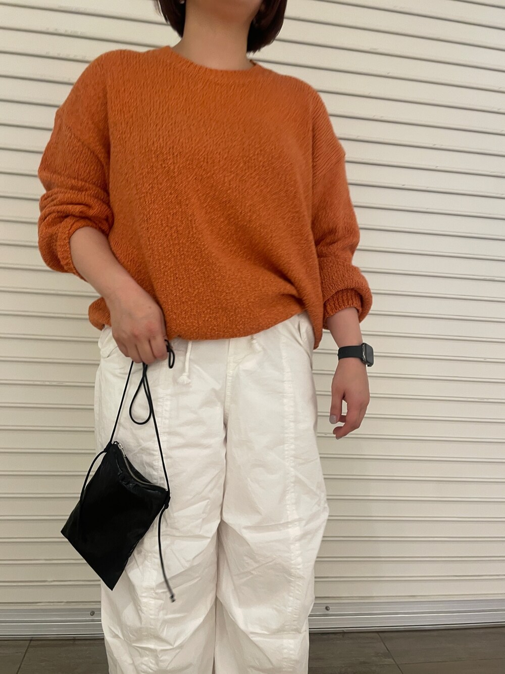 オレンジ系のニット/セーター、ホワイト系のその他パンツ、ゴールド系のパンプスを着用したレディースの冬コーディネートの7枚目の写真