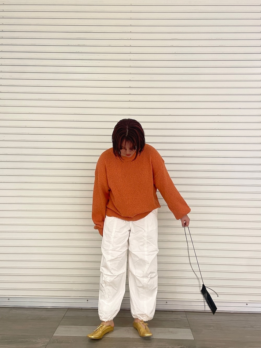 オレンジ系のニット/セーター、ホワイト系のその他パンツ、ゴールド系のパンプスを着用したレディースの冬コーディネートの2枚目の写真