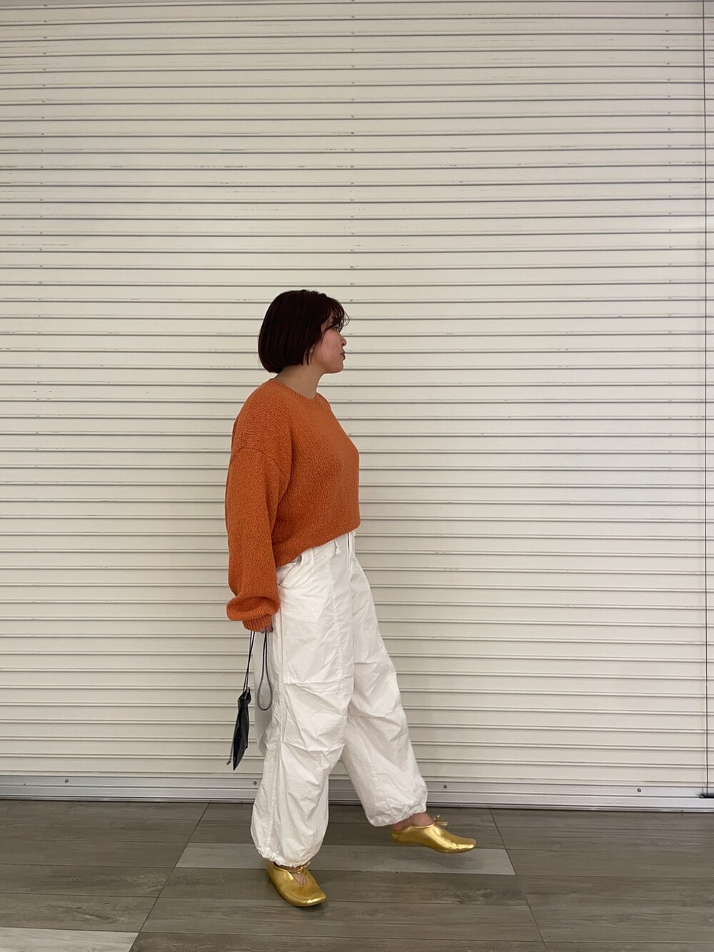 オレンジ系のニット/セーター、ホワイト系のその他パンツ、ゴールド系のパンプスを着用したレディースの冬コーディネートの3枚目の写真