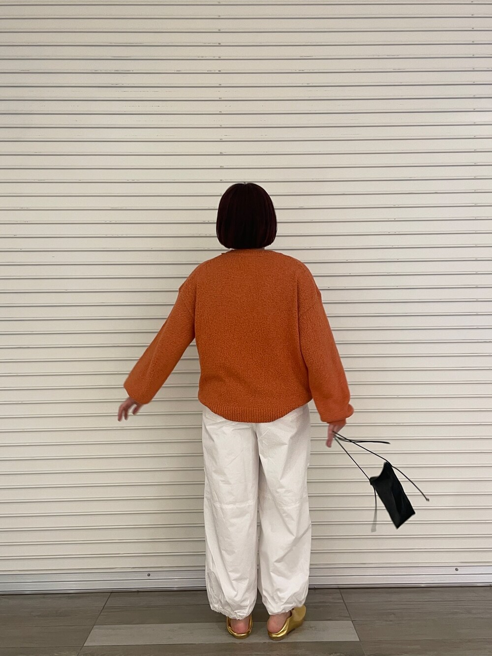 オレンジ系のニット/セーター、ホワイト系のその他パンツ、ゴールド系のパンプスを着用したレディースの冬コーディネートの4枚目の写真