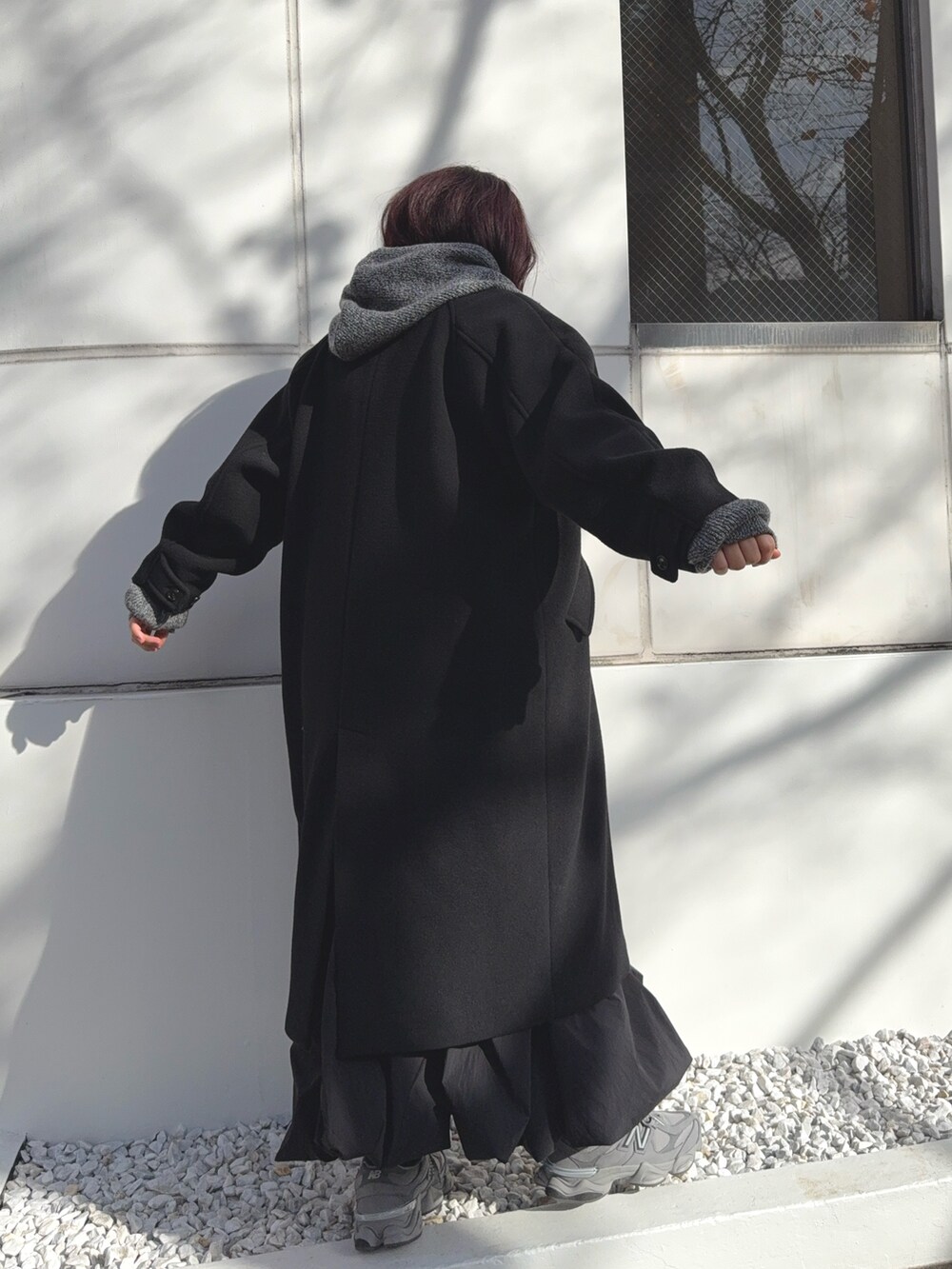 ブラック系のチェスターコート、グレー系のニット/セーターを着用したレディースの冬コーディネートの3枚目の写真