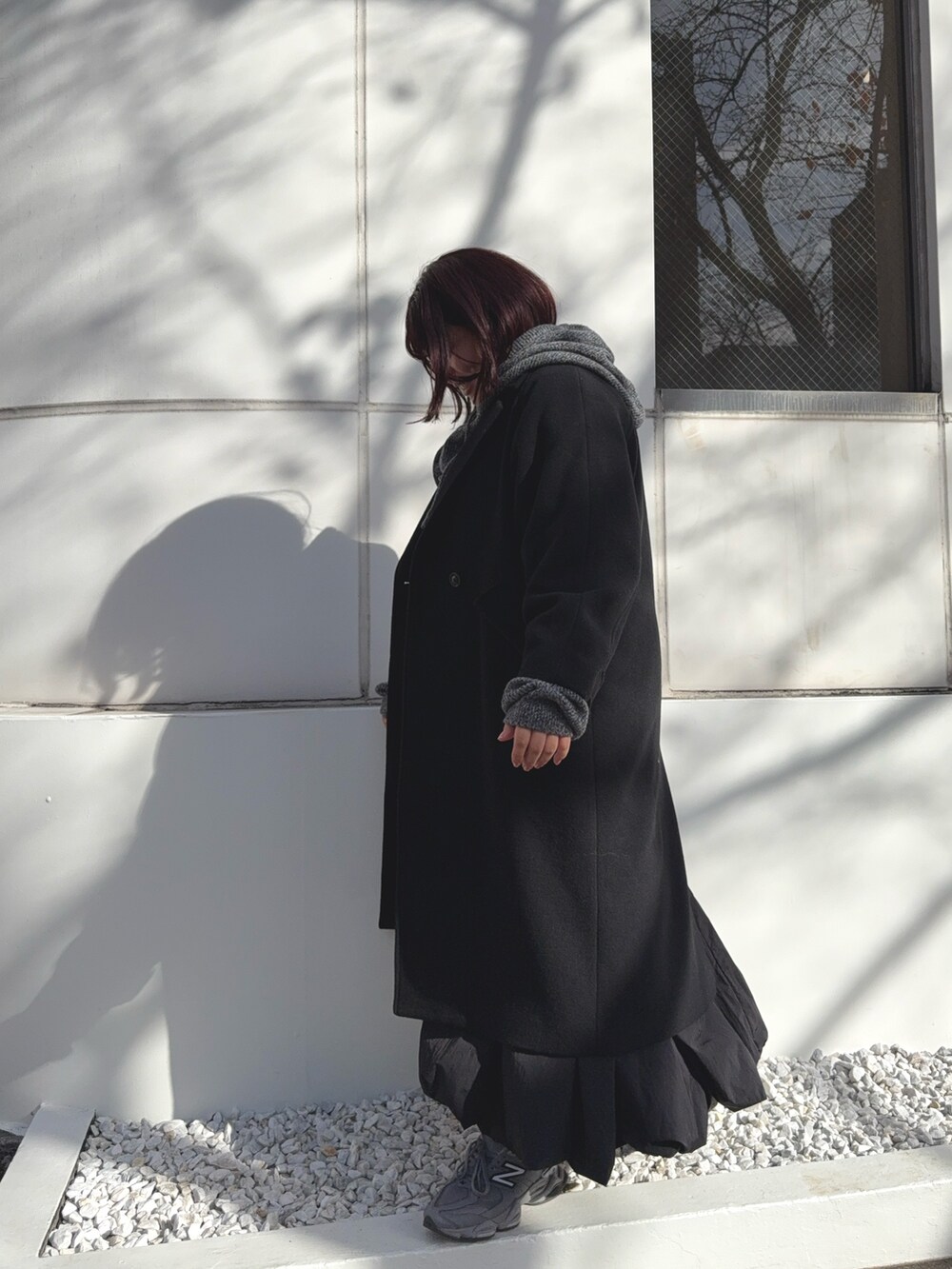 ブラック系のチェスターコート、グレー系のニット/セーターを着用したレディースの冬コーディネートの4枚目の写真