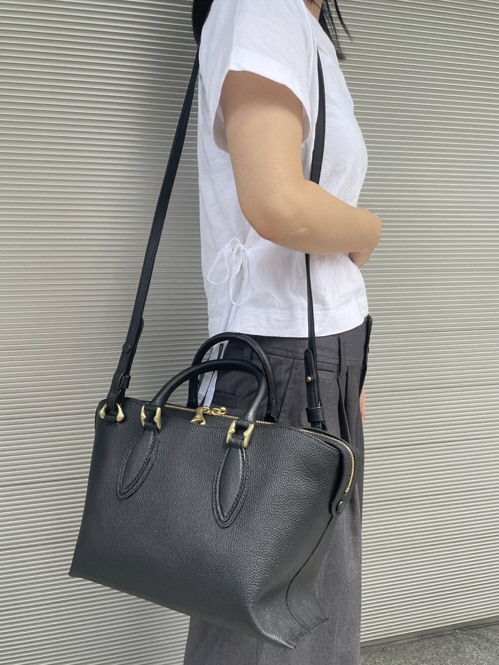 ホワイト系のTシャツ/カットソー、ブラック系のハンドバッグ、イエロー系のスニーカーを着用したレディースの春コーディネートの2枚目の写真