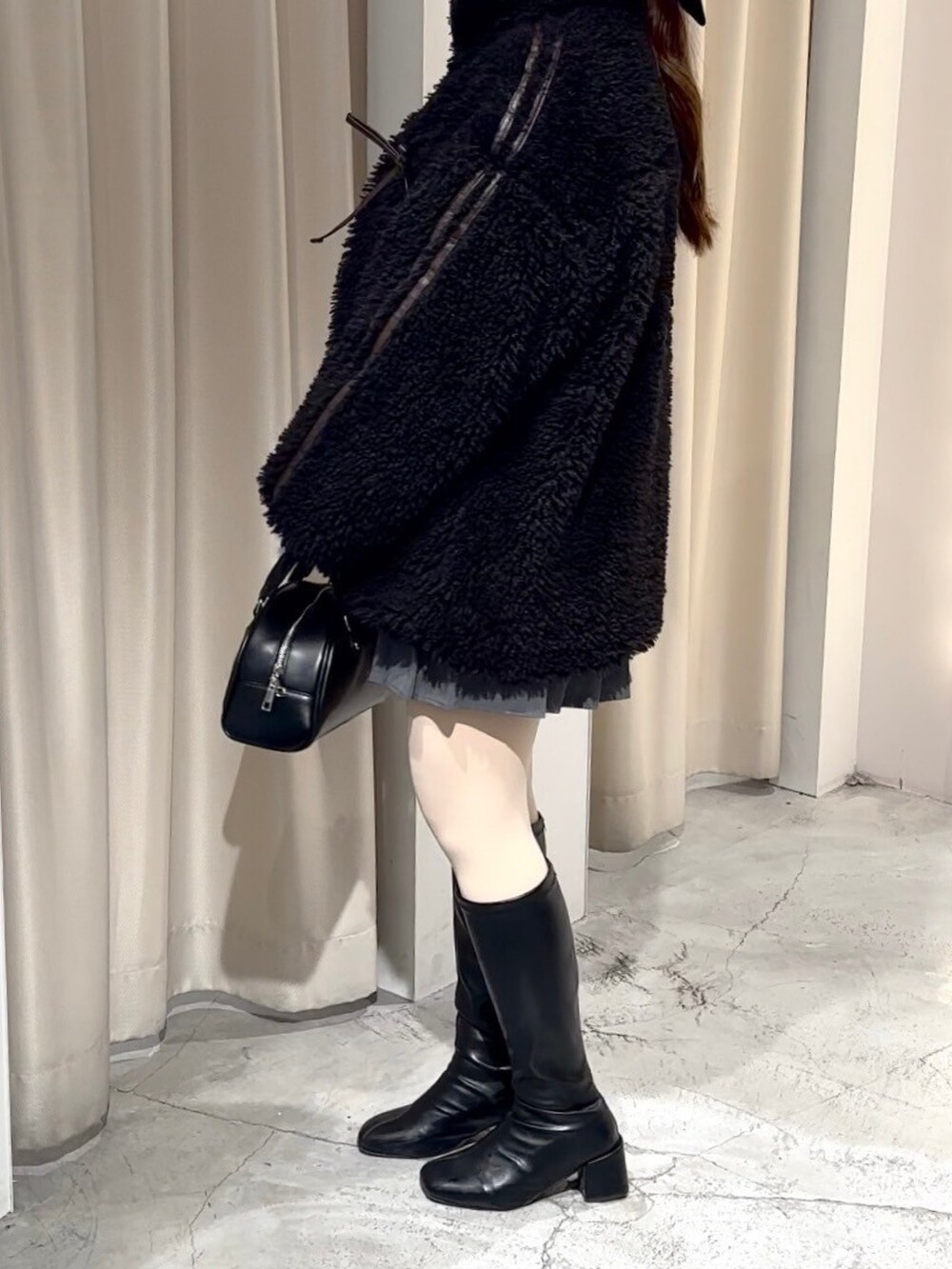 ブラック系のブルゾン、ブラック系のハンドバッグ、グレー系のスカートを着用したレディースの冬コーディネートの6枚目の写真