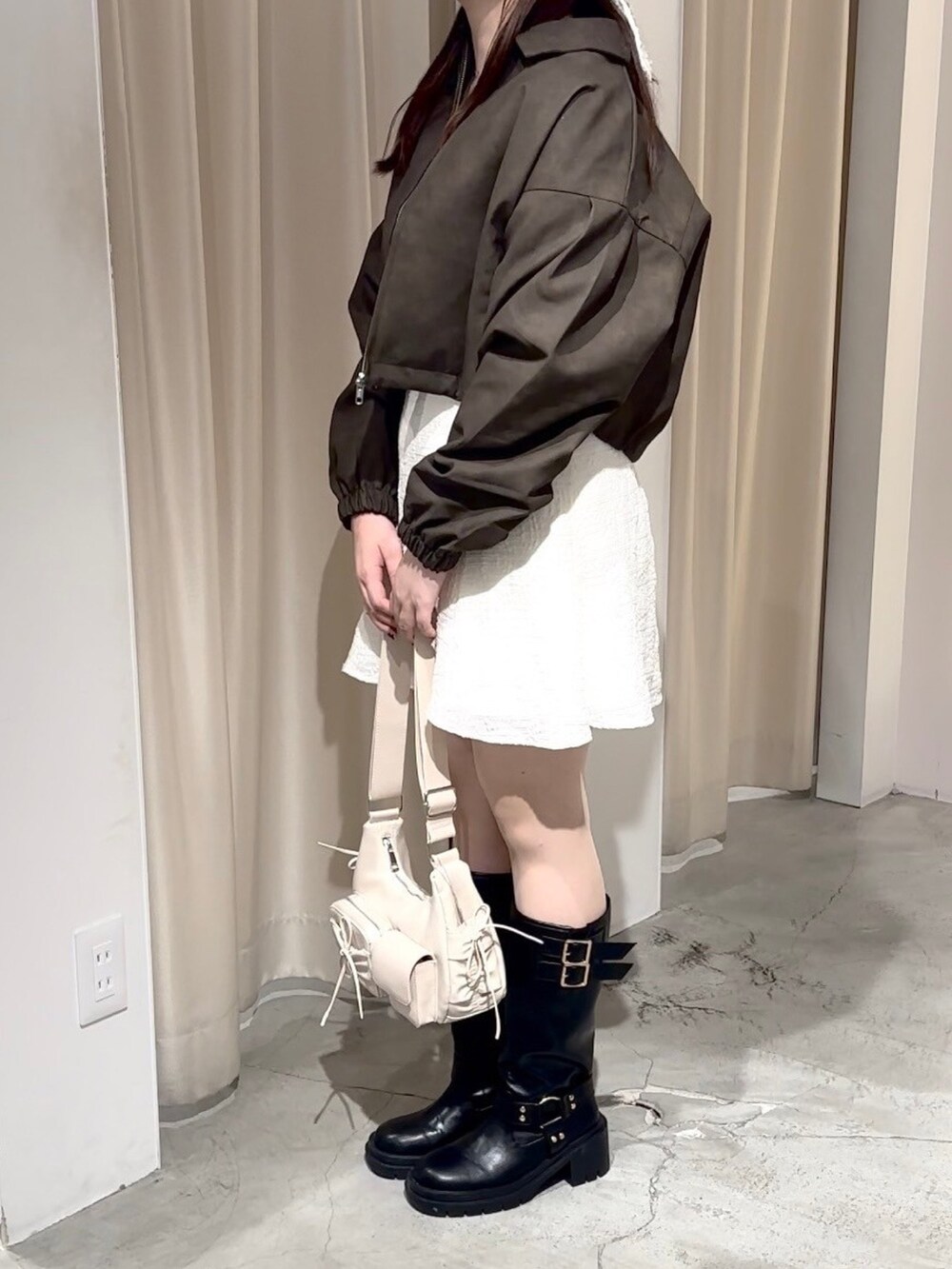 ベージュ系のワンピース、ホワイト系のショルダーバッグ、ブラック系のブーツを着用したレディースの秋コーディネートの7枚目の写真