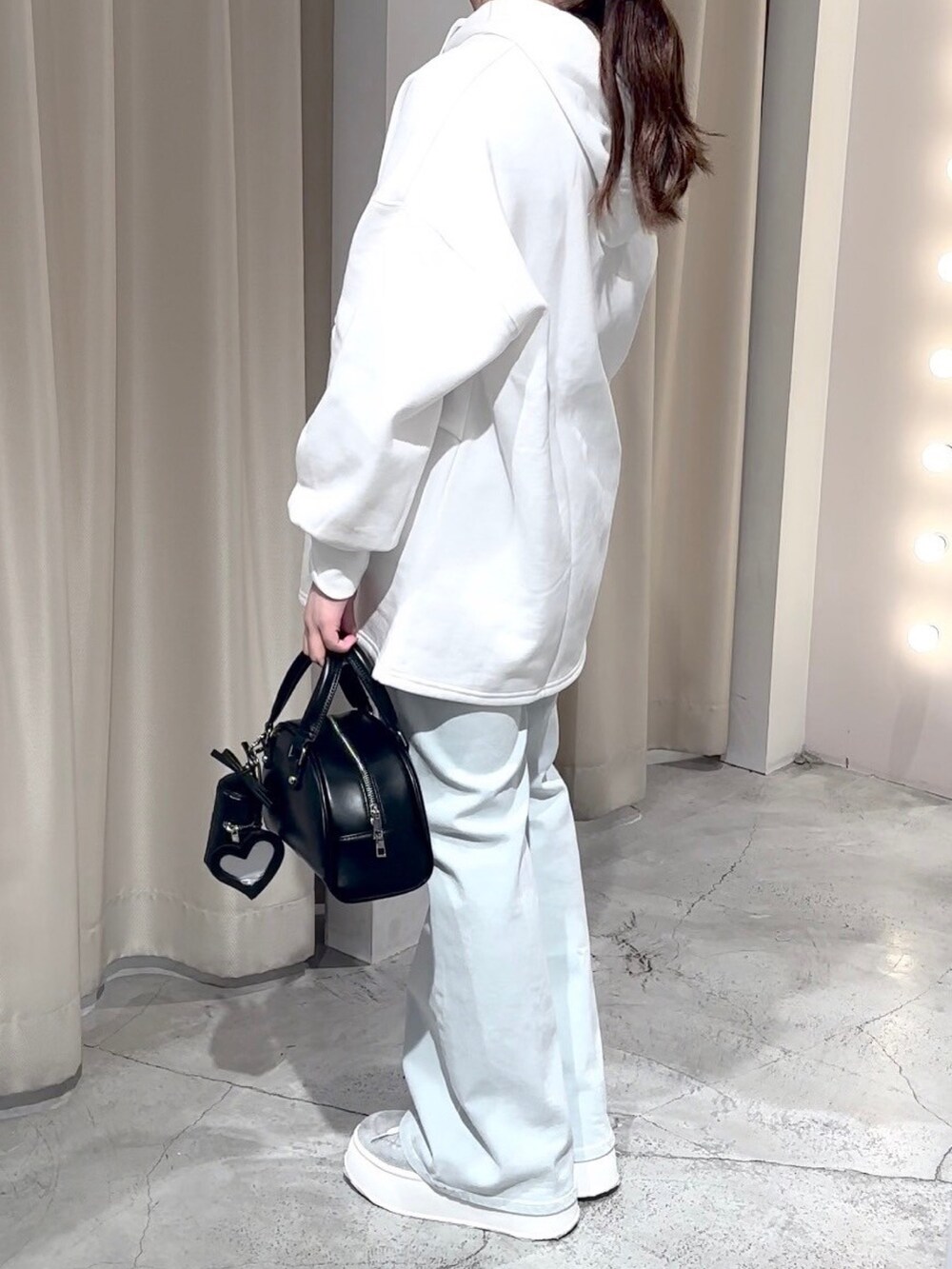 ホワイト系のパーカー、ブラック系のハンドバッグ、ブルー系のデニムパンツを着用したレディースの冬コーディネートの3枚目の写真