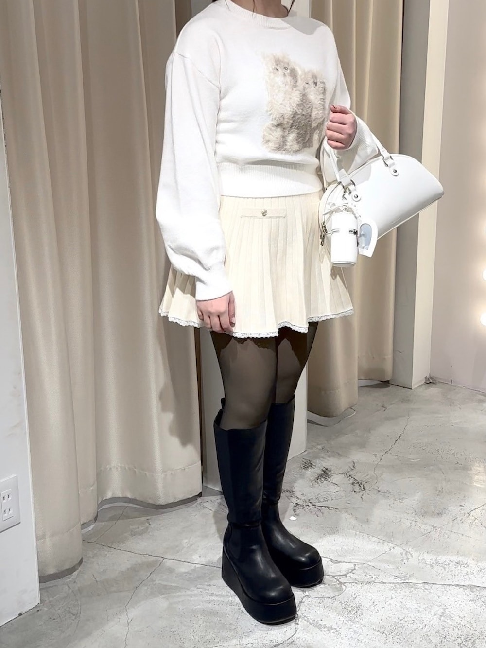 ホワイト系のニット/セーター、ホワイト系のワンピース、ホワイト系のハンドバッグを着用したレディースの冬コーディネートの3枚目の写真