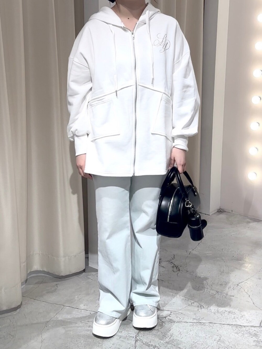 ホワイト系のパーカー、ブラック系のハンドバッグ、ブルー系のデニムパンツを着用したレディースの冬コーディネートの5枚目の写真