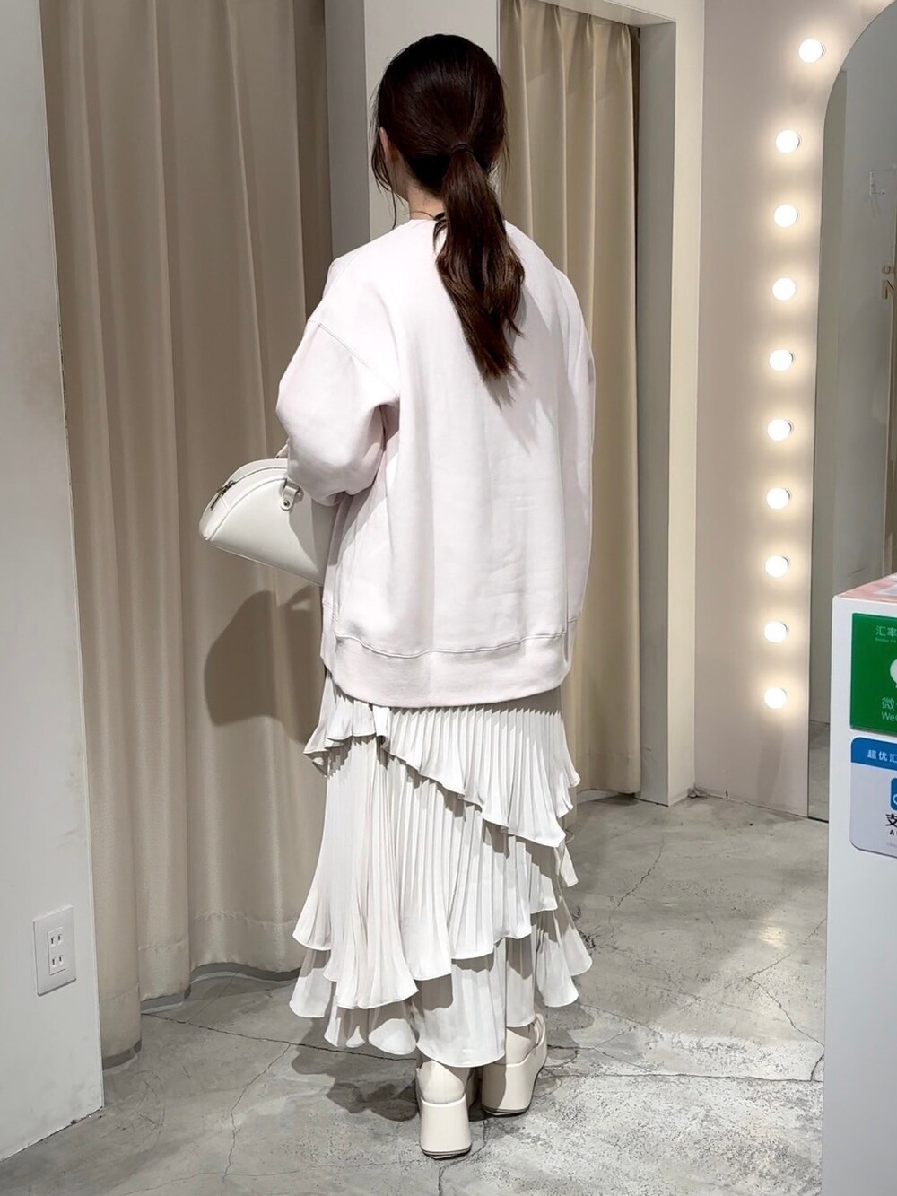 ピンク系のスウェット、ホワイト系のハンドバッグ、ホワイト系のスカートを着用したレディースの冬コーディネートの5枚目の写真