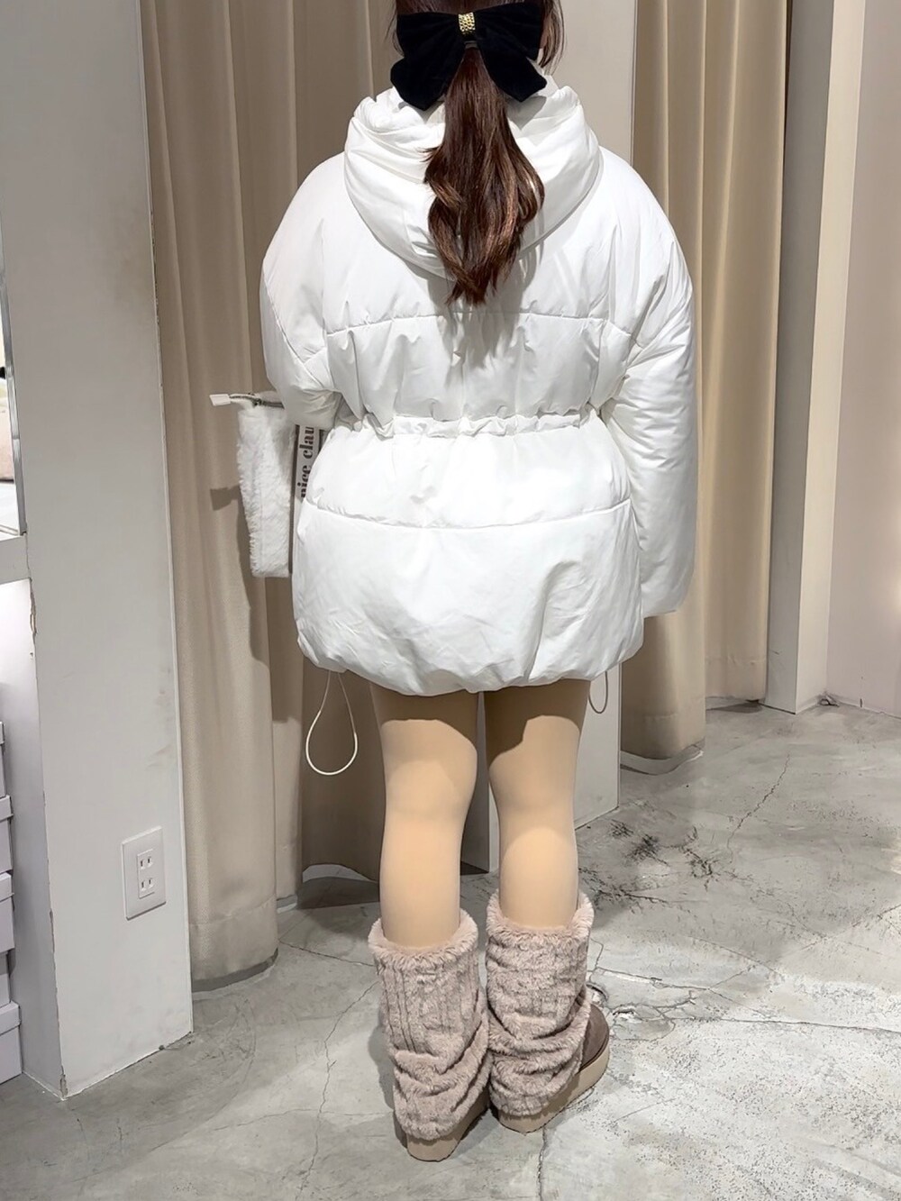 ホワイト系のダウンジャケット/コート、ホワイト系のトートバッグ、ブラウン系のブーツを着用したレディースの冬コーディネートの5枚目の写真