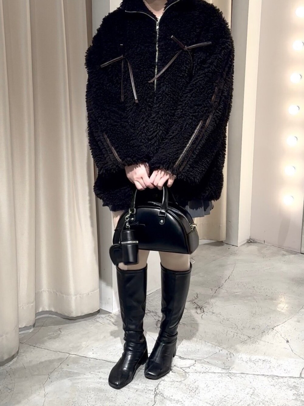 ブラック系のブルゾン、ブラック系のハンドバッグ、グレー系のスカートを着用したレディースの冬コーディネートの5枚目の写真