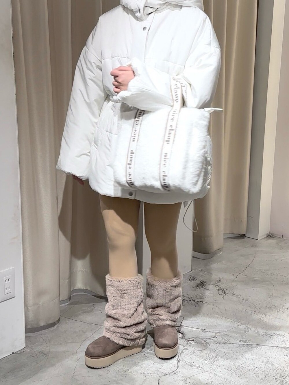 ホワイト系のダウンジャケット/コート、ホワイト系のトートバッグ、ブラウン系のブーツを着用したレディースの冬コーディネートの2枚目の写真