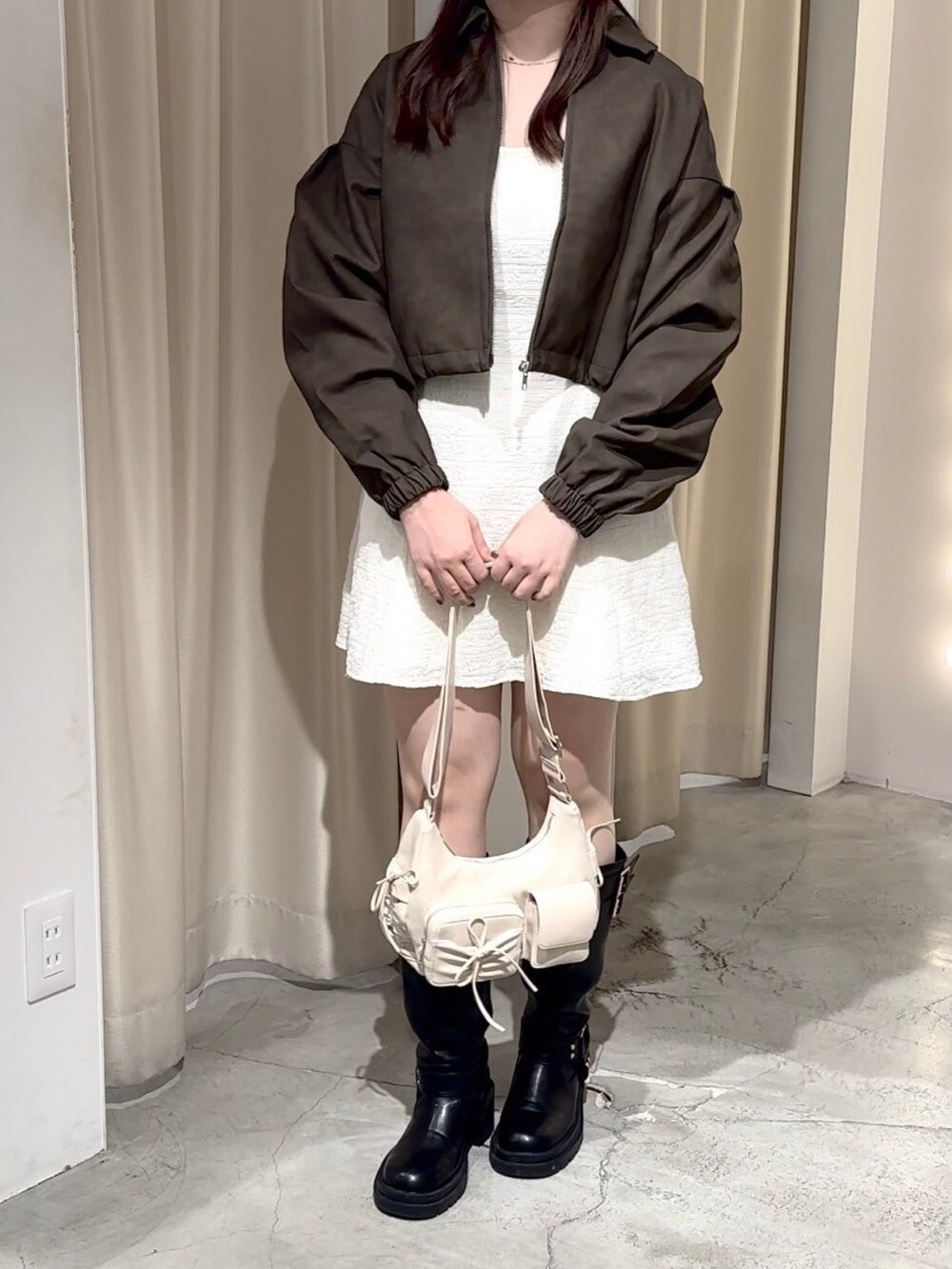 ベージュ系のワンピース、ホワイト系のショルダーバッグ、ブラック系のブーツを着用したレディースの秋コーディネートの6枚目の写真