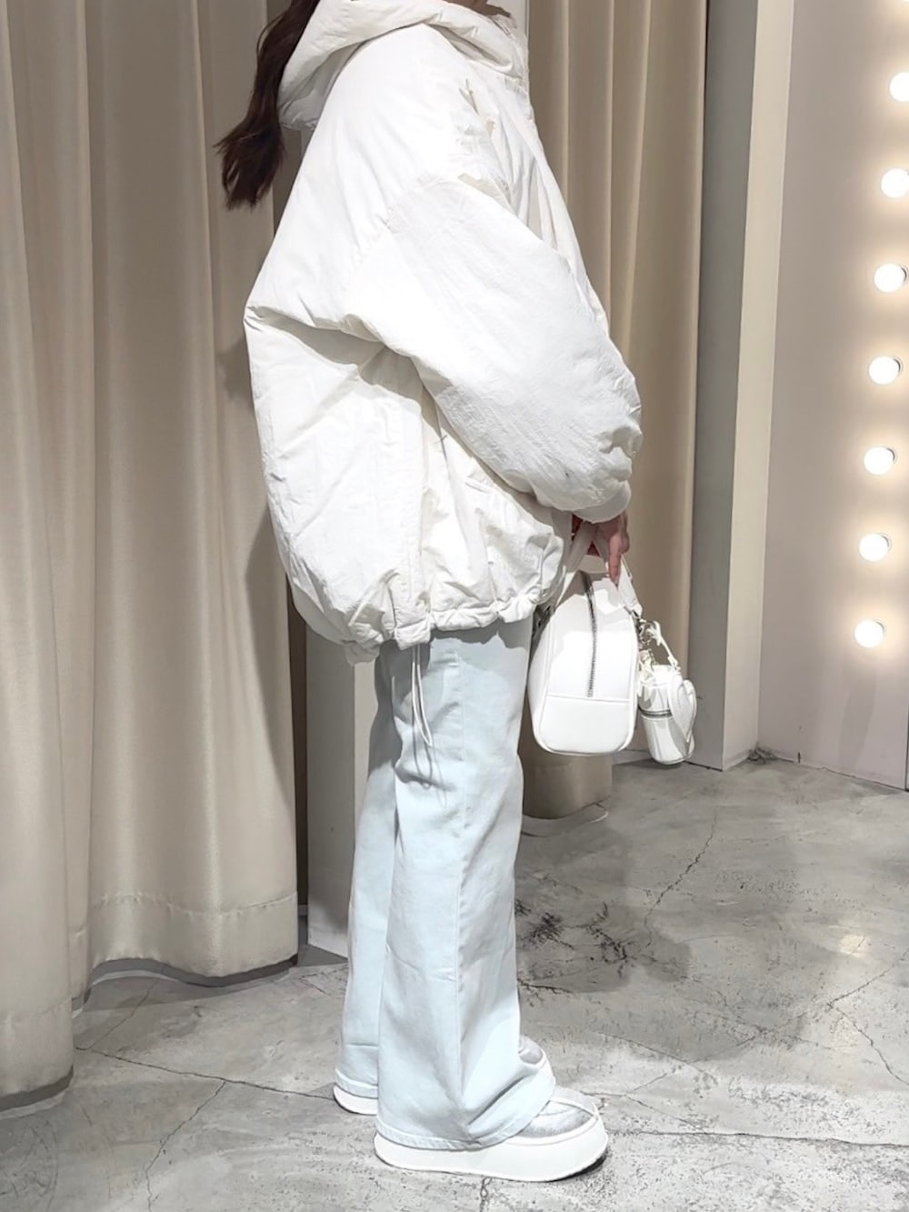 ホワイト系のブルゾン、ホワイト系のハンドバッグ、ブルー系のデニムパンツを着用したレディースの冬コーディネートの2枚目の写真
