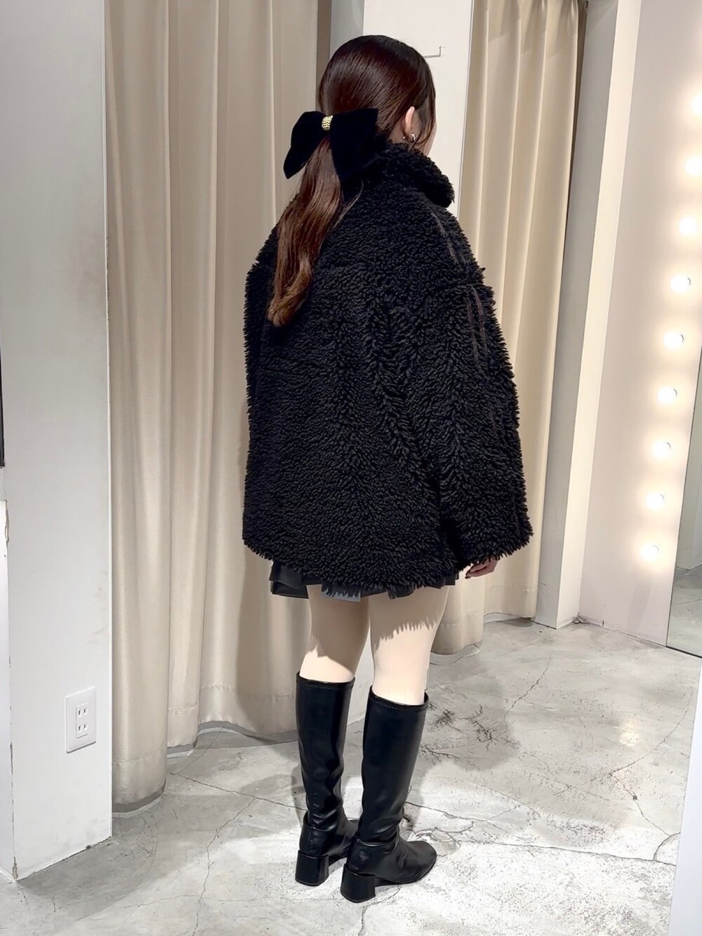 ブラック系のブルゾン、ブラック系のハンドバッグ、グレー系のスカートを着用したレディースの冬コーディネートの3枚目の写真