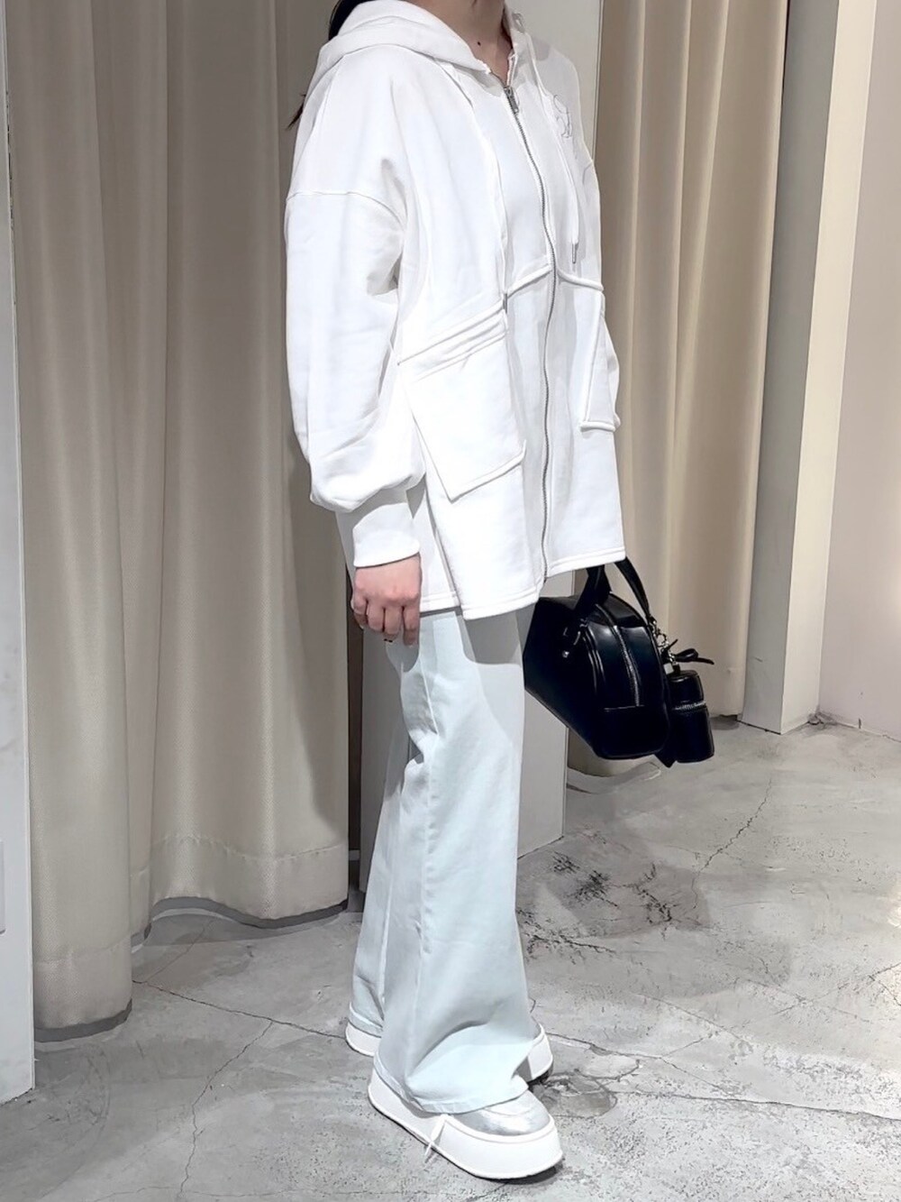 ホワイト系のパーカー、ブラック系のハンドバッグ、ブルー系のデニムパンツを着用したレディースの冬コーディネートの6枚目の写真