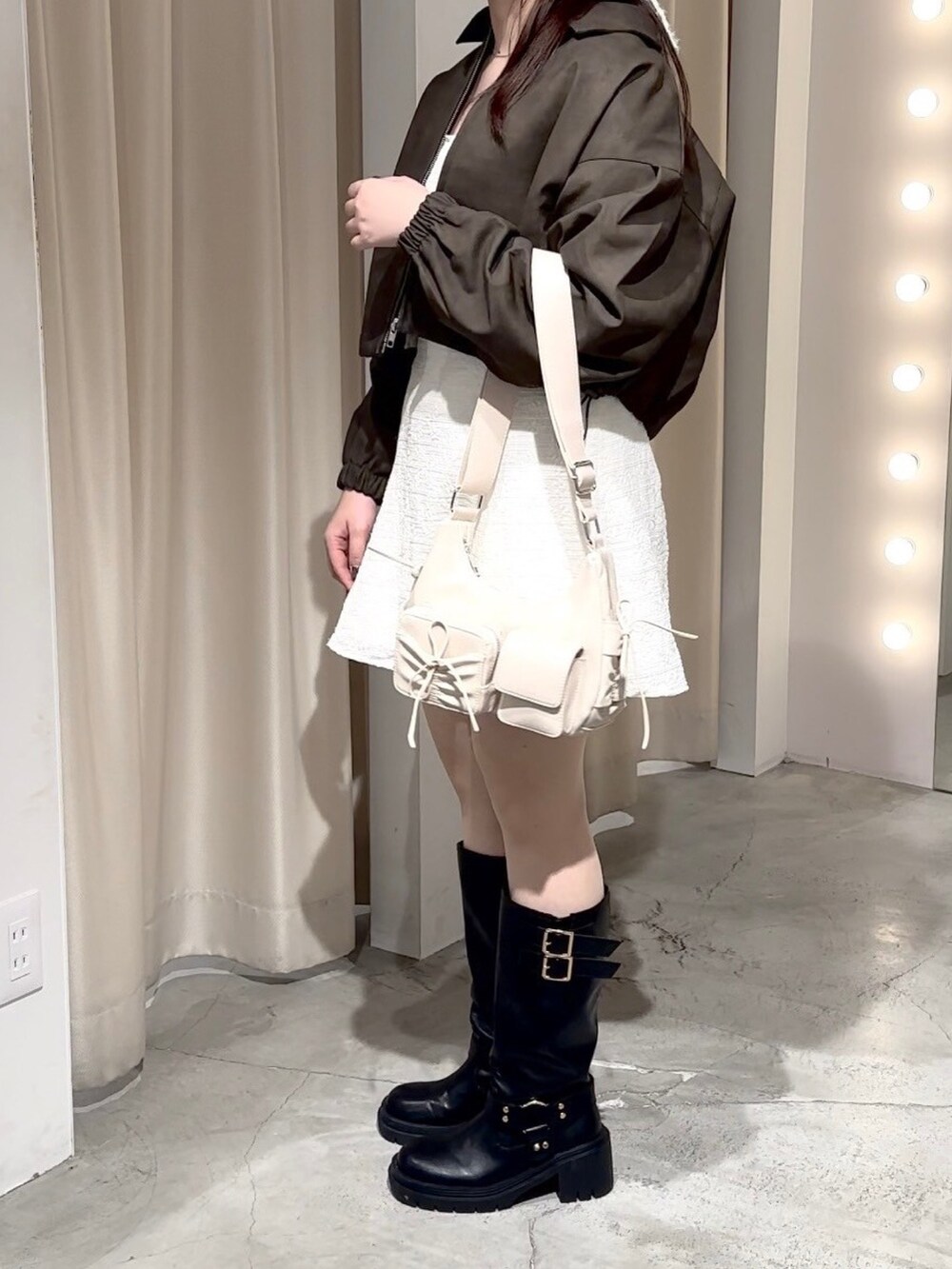 ベージュ系のワンピース、ホワイト系のショルダーバッグ、ブラック系のブーツを着用したレディースの秋コーディネートの3枚目の写真