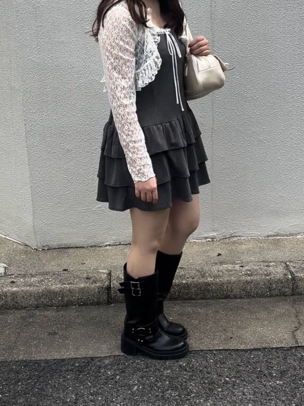 グレー系のワンピース、ホワイト系のボストンバッグ、ブラック系のブーツを着用したレディースの秋コーディネートの3枚目の写真