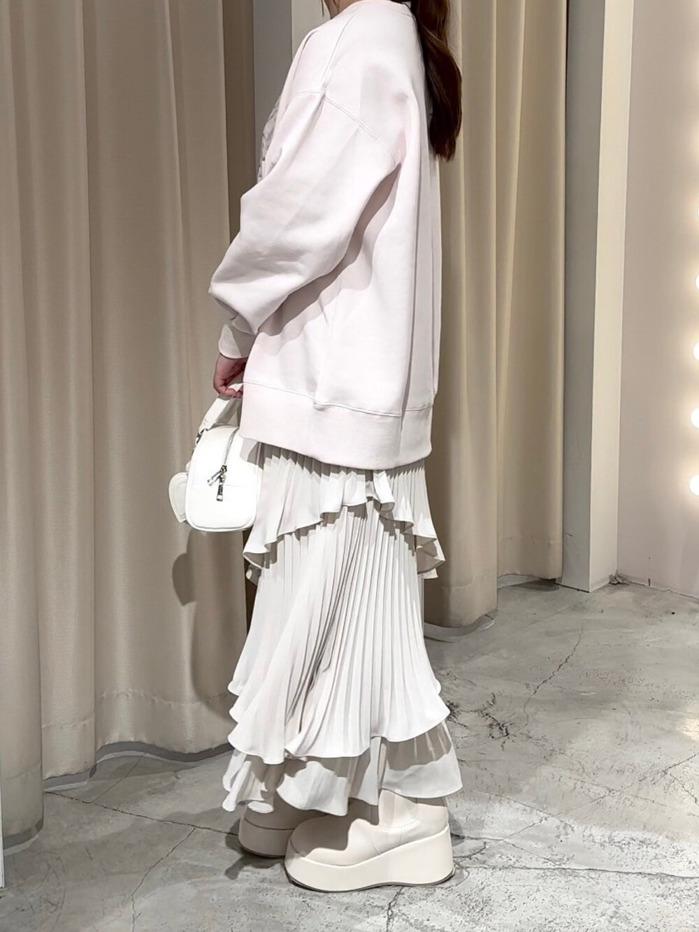 ピンク系のスウェット、ホワイト系のハンドバッグ、ホワイト系のスカートを着用したレディースの冬コーディネートの2枚目の写真