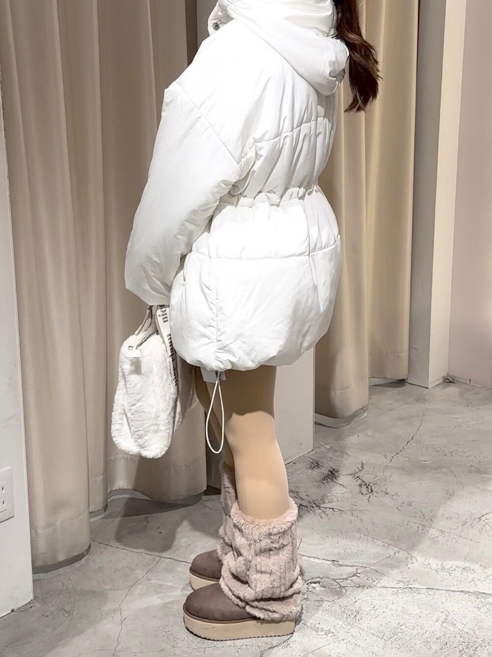 ホワイト系のダウンジャケット/コート、ホワイト系のトートバッグ、ブラウン系のブーツを着用したレディースの冬コーディネートの3枚目の写真